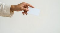 Hand holding blank white card isolated on light background, suitable for business cards, invitations, and promotional designs.