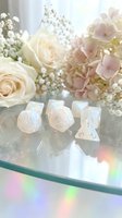 Opalescent polyhedral dice set with cream roses, pink hydrangeas, and baby's breath flowers on reflective surface for tabletop gaming.