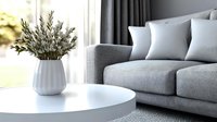 Modern living room interior with gray sofa, white round coffee table and olive branches in ceramic vase, minimalist home decor against bright window.