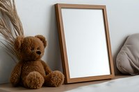 Brown wooden frame mockup with teddy bear and pampas grass on shelf against white wall, modern minimalist home decor styling for nursery or children room.