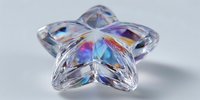 Crystal star-shaped prism displaying rainbow light refraction and optical effects on white background for jewelry and decoration concepts.