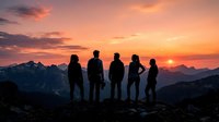 Group of five people standing on mountain ridge at sunset, silhouetted against golden and orange sky with distant peaks, representing teamwork, adventure and outdoor exploration.