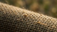 Natural burlap fabric texture with woven jute fibers in warm brown tones, rustic material background for eco-friendly packaging and craft projects.