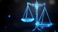 Glowing blue scales of justice on dark background with digital particle effect, symbolizing law technology and digital transformation in legal industry.