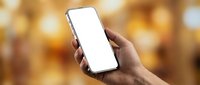 Hand holding smartphone with blank white screen against warm golden bokeh background, suitable for app mockups, mobile advertising, and digital marketing campaigns.