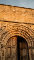 Ornate stone archway entrance with intricate carved details and wooden doors on historic building facade for architectural design projects.