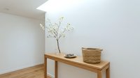 Minimalist wooden console table with wicker basket and decorative branch in modern white interior room for home decor and furniture design.