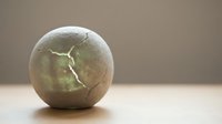 Cracked stone sphere with jagged fracture line across surface, isolated on neutral background for design and composite projects.