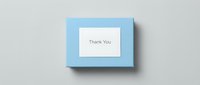 Light blue gift box with a white thank you card on top, shot from above on a neutral gray background for greeting and packaging concepts.