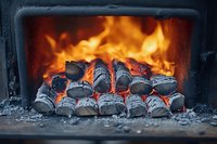 Glowing hot charcoal briquettes burning in fireplace with bright orange flames and embers, creating warm atmospheric lighting for cozy winter ambiance.