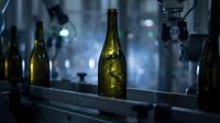 Empty wine bottle with golden glass on dark shelf against blurred blue-toned background, suitable for beverage, alcohol, and hospitality design projects.