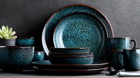 Elegant teal ceramic dinnerware set with speckled glaze finish and dark rim accents displayed on dark surface with succulent plant for modern kitchen styling.