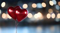 Red heart shaped balloons against blurred bokeh lights background creating romantic atmosphere. Valentine's day celebration concept with copy space for text.