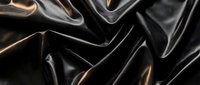 Luxurious black silk fabric with flowing folds and dramatic lighting creates elegant textile background for fashion and design projects.