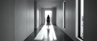Woman standing in modern minimalist hallway with natural light streaming through windows, contemporary interior design for architectural and lifestyle projects.