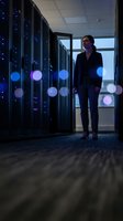 Professional woman IT specialist standing in modern server room with glowing blue lights and network equipment for technology and data center concepts.