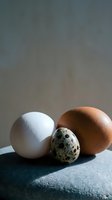 Three different eggs on dark surface showcasing variety in size and color for culinary and cooking concepts.