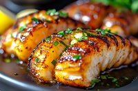 Grilled salmon fillets glazed with honey soy sauce, garnished with fresh herbs and green onions, served on dark plate with caramelized surface and juicy texture.