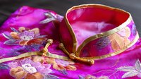 Traditional Asian mandarin collar in bright fuchsia silk with gold embroidered floral pattern and decorative frog closures, showcasing detailed oriental craftsmanship.