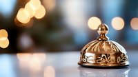 Luxury hotel service bell on reception desk with warm bokeh lights creating elegant hospitality atmosphere for premium guest experience and concierge services.