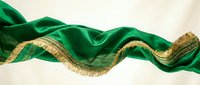 Luxurious emerald green silk ribbon with gold metallic trim edges, flowing in elegant waves against neutral background for design projects.