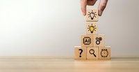 Hand placing wooden cube with lightbulb icon on stack of blocks featuring AI, question mark, and gear symbols representing innovation and problem-solving.