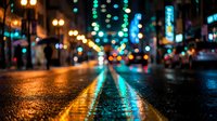 Blurred city street at night with colorful neon lights reflecting on wet asphalt pavement creating vibrant bokeh effect for urban nightlife backgrounds.