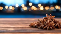 Star anise pods on rustic wooden surface with blurred golden bokeh lights in background creating festive holiday atmosphere for seasonal cooking and decoration.