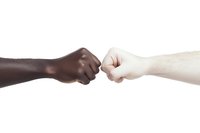 Black and white hands making fist bump gesture against white background, symbolizing unity, racial equality, friendship and solidarity in modern society.