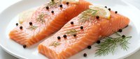 Fresh raw salmon fillets with dill and peppercorns on white plate ready for cooking. Healthy omega-3 rich fish protein for gourmet meals and recipes.