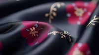 Elegant black silk fabric with golden floral embroidery and burgundy accents flowing gracefully for luxury fashion and textile design projects.
