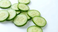 Fresh cucumber slices arranged on white background, perfect for healthy eating, cooking, spa treatments and natural skincare applications.