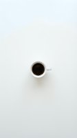 White coffee cup with black coffee on clean white background, minimalist overhead view for cafe branding and beverage marketing materials.