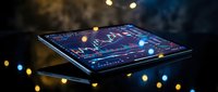 Digital tablet displaying financial trading charts and market data analysis with colorful bokeh lights creating atmospheric business technology scene.
