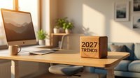 Modern workspace with wooden cube displaying 2027 trends text on desk beside computer monitor and plant in bright office setting for business planning.