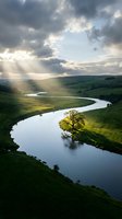 Meandering river winds through lush green rolling hills under dramatic cloudy sky with golden sunlight breaking through clouds, suitable for landscape and nature backgrounds.