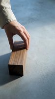 Hand reaching for wooden block on concrete surface showcasing minimalist design and natural materials in modern architectural setting.