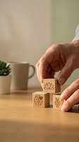 Hands arranging wooden blocks with wellness symbols including lotus flower, brain, and heart on desk for mindfulness and mental health concept.