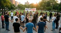 Diverse group of people holding hands in circle around unity banner in urban park during golden hour sunset community gathering for social change activism.