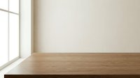 Empty wooden table surface near window with natural light for product display and interior design mockups.