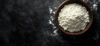 White flour in rustic wooden bowl on dark textured background with copy space. Top view of baking ingredient for homemade bread and pastry making.