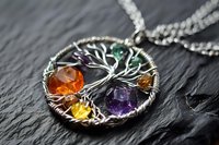 Tree of life pendant with colorful gemstones on silver chain against dark slate background. Handcrafted jewelry with wire wrapping technique.