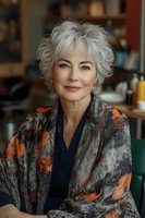 Confident mature woman with silver hair wearing stylish orange and gray patterned shawl smiles warmly at camera. Natural beauty and aging gracefully concept.