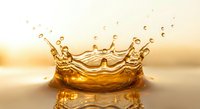 Golden liquid crown splash with droplets frozen in motion against warm sunset background creating dynamic fluid art for beverage and luxury concepts.