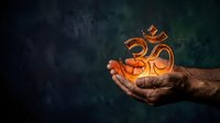 Male hand holding glowing orange om symbol against dark teal background. Spiritual meditation and yoga concept for wellness, mindfulness, and eastern philosophy practices.