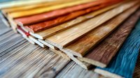 Wood texture samples in fan arrangement showing various colors and grains of hardwood flooring materials on blue background, close-up view for interior design.