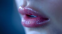 Close-up of glossy pink lips with soft blue lighting, showcasing natural texture and subtle shine for beauty and cosmetic advertising.