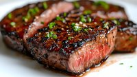 Juicy grilled beef steak with caramelized crust, medium rare doneness, garnished with fresh chopped herbs and glazed with savory sauce. Close up food photography.