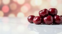 Fresh red cranberries on white marble surface with warm bokeh lights background for holiday cooking and festive seasonal recipes.