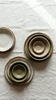 Handmade ceramic bowls in earthy tones arranged on white linen fabric, showcasing artisan pottery craftsmanship for kitchen and dining decor.